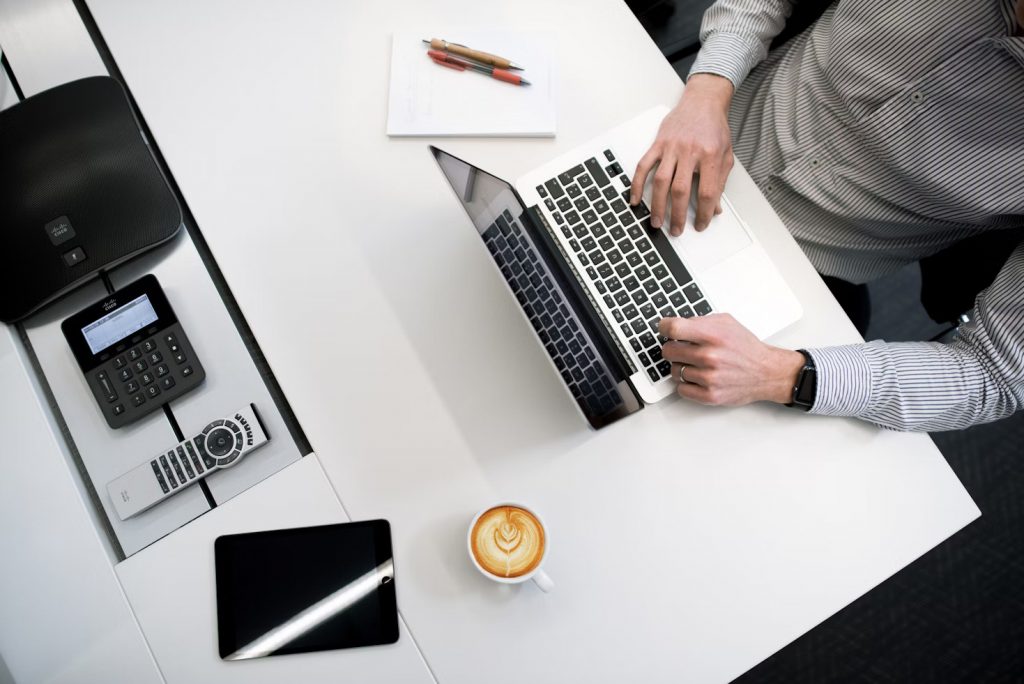 Persona Usando Portatil Sobre Mesa Blanca De Madera