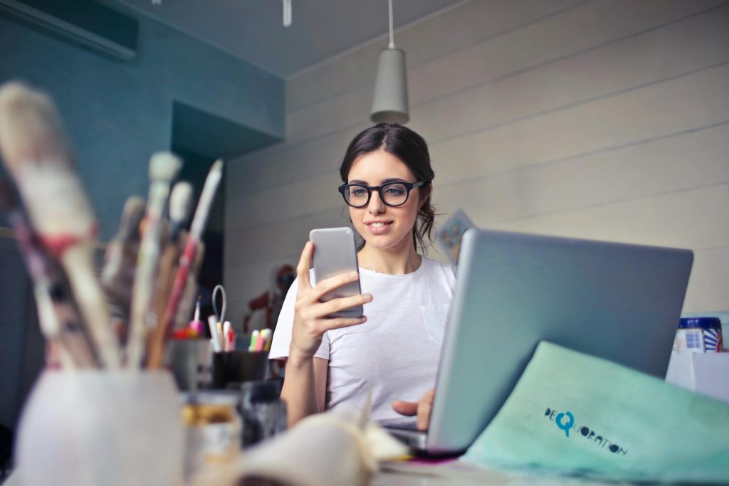 Donna Tiene Smartphone Accanto A Un Portatile
