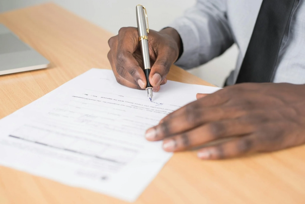 Person holding gray Pen and Printer Paper on Table